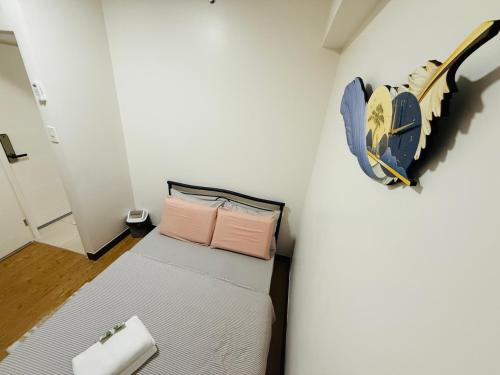 a small bedroom with a bed and a painting on the wall at JFam Suites Allegra Condo with Balcony, FREE Parking in Manila