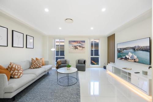 a living room with a couch and a table at 6BR House & Gym Walk to Moorebank Train Station in Moorebank