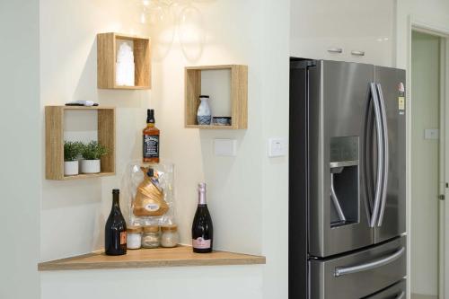 a kitchen with a refrigerator and bottles of wine on a shelf at 6BR House & Gym Walk to Moorebank Train Station in Moorebank