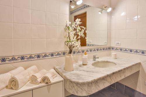 ein Badezimmer mit einem Waschbecken und einer Vase mit Blumen in der Unterkunft La Lunaria di Lajatico in Laiatico