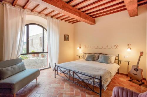 ein Schlafzimmer mit einem Bett, einem Stuhl und einer Gitarre in der Unterkunft La Lunaria di Lajatico in Laiatico