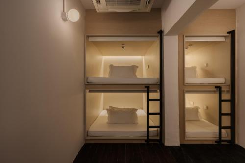 a room with four bunk beds with a mirror at BEAT 1932 Hostel at Chinatown in Singapore