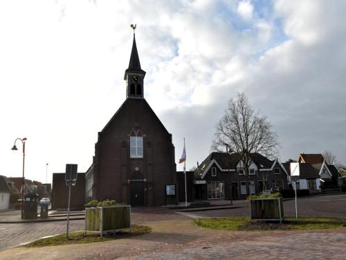 a church with a steeple on the side of a street at Group home with sauna near the beach and sea in Julianadorp