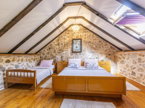 two beds in a attic bedroom with stone walls at Rustical Resort Kokori i with Shared Outdoor Swimming Pool - One Bedroom Apartment with Terrace in Višnjica