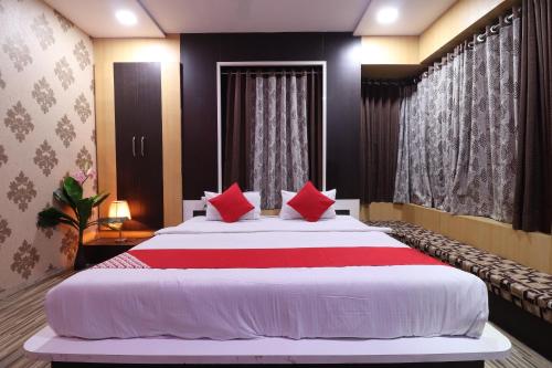 a bedroom with a large bed with red pillows at Hotel O Shri Sai Niwara Lodge in Dhule