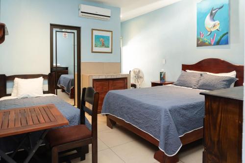 a bedroom with two beds and a table and a desk at Hotel la Cueva Limon in Puerto Limón