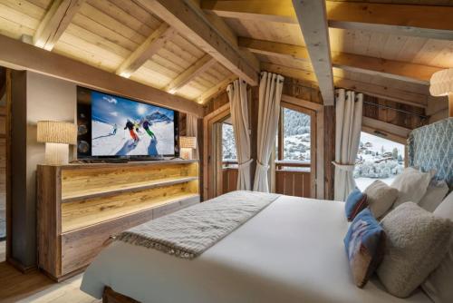 ムジェーヴにあるLuxury Megeve Chalet 4BR 10p Fireplace Mountain Views and Gardenのキャビン内の大きなベッドとテレビのある寝室