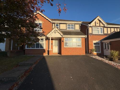 ein Backsteinhaus mit einer Einfahrt davor in der Unterkunft Sycamore Retreat in Kettering