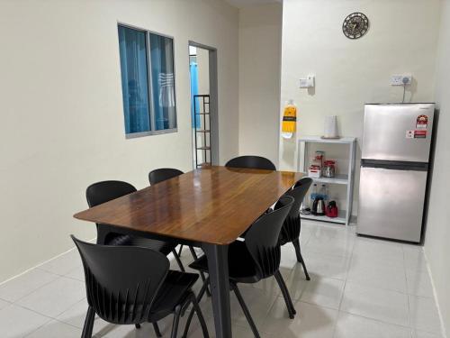 a dining room with a wooden table and black chairs at Homestay Tok in Tapah Road
