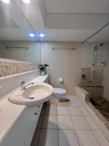 a white bathroom with a sink and a toilet at Rainbow Beach Resort overlooking Pool in Rainbow Beach