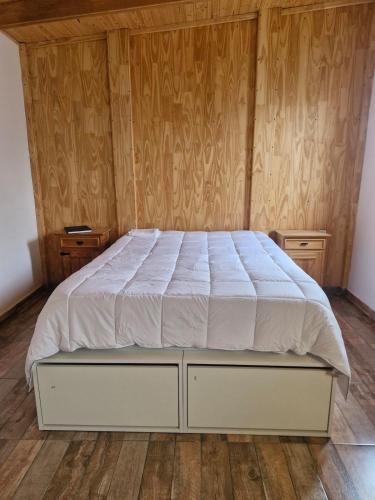 Cama en habitación con paredes y suelo de madera en Rincón del Shoam, en Gobernador Gregores