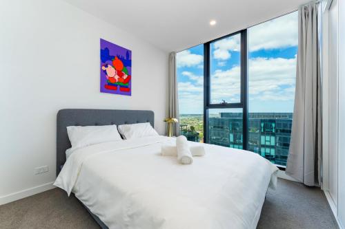 a bedroom with a white bed with a large window at Spacious 4BR penthouse in Box Hill Free Parking x 2 in Box Hill