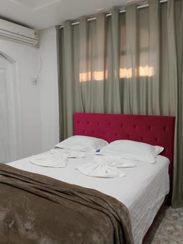a large bed with a red headboard in a bedroom at Hotel Pompéia em Almeirim 