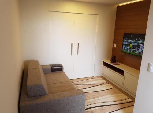 a small living room with a couch and a tv at Apartamento com varanda e vista da Pedra Azul in Domingos Martins