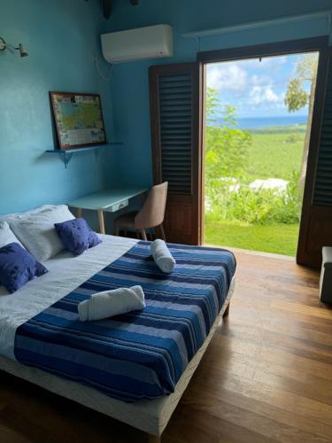 a bedroom with a bed and a table and a window at Hélios Zion in Capesterre-Belle-Eau
