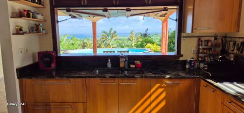 cocina con fregadero y ventana con vistas a la piscina en Hélios Zion, en Capesterre-Belle-Eau