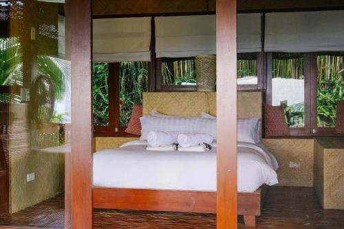 a bedroom with a bed with white sheets and windows at Narra Hill Tagaytay in Laurel