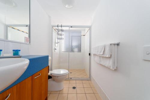 a bathroom with a shower and a toilet and a sink at Spacious Mantra Hotel Room in Urangan