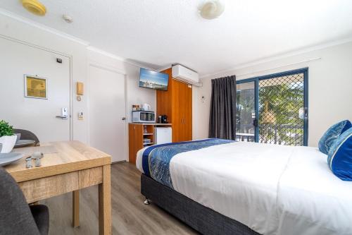 a bedroom with a bed and a desk and a window at Spacious Mantra Hotel Room in Urangan