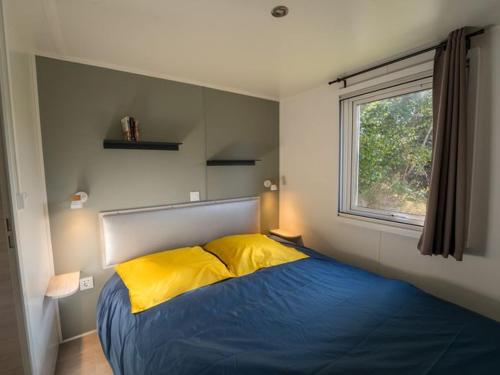 una camera da letto con un letto con cuscini gialli e una finestra di Mobil home 36m² avec terrasse - 6 personnes, 3 chambres - API-1-52-530 a Barbey-Séroux