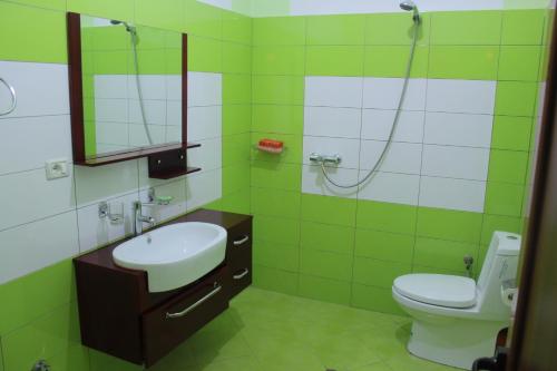 ein grünes Bad mit einem Waschbecken und einem WC in der Unterkunft Alen Bar Hotel in Tirana