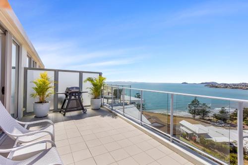 a balcony with chairs and a view of the ocean at Luxe at Oshen Yeppoon in Yeppoon