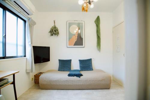 a bedroom with a bed with blue pillows and a tv at 伊勢神宮内宮前-民泊宿i s e s h i m a -201 in Ise
