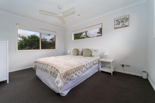 a white bedroom with a bed and a window at Scarness Spacious Home with Pool in Scarness