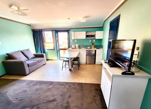 a living room with a couch a television and a kitchen at Pure Motel in Rotorua