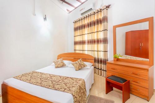a bedroom with a bed and a dresser and a mirror at Roamers Ark Galle in Galle