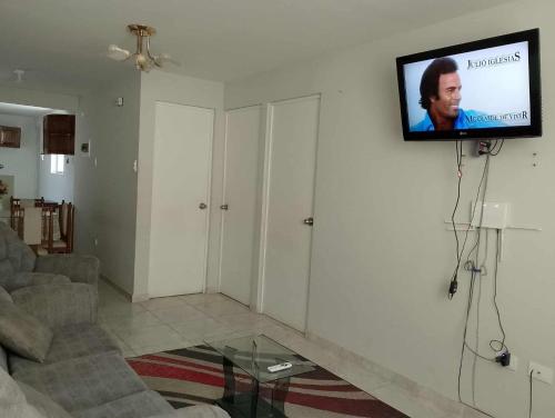 a living room with a couch and a tv on a wall at Casa en Lambayeque in Lambayeque
