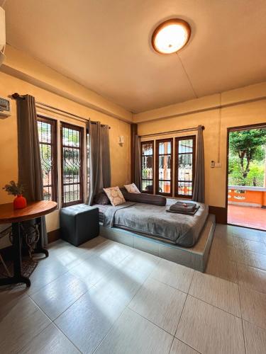 a bedroom with a bed and a table and windows at Baan Mali Koh Kood in Ban Hin Dam