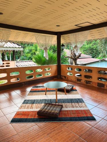 a living room with a table and a rug at Baan Mali Koh Kood in Ban Hin Dam