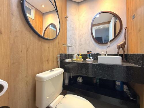 Un baño con inodoro, lavabo y espejo. en Casa de condominio mobiliada Prox. MOTOGP, en Goiânia