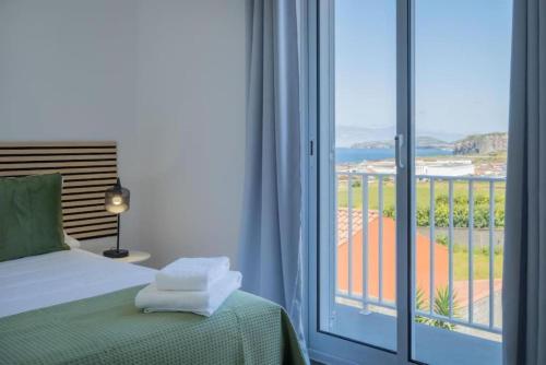 Rabo de PeixeにあるVila da Pesca Houseのベッドルーム1室(ベッド1台付)、景色を望むバルコニーが備わります。