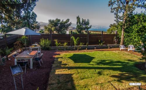 a yard with a table and chairs and an umbrella at Beautiful Lake View Wooden House in Tiberias