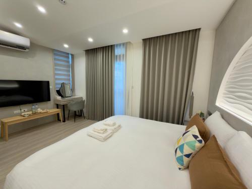 a hotel room with a large white bed and a desk at 眺浪島民宿 in Fan-shu-liao