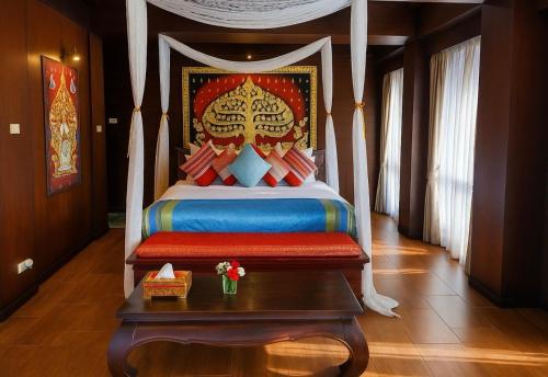 ein Schlafzimmer mit einem großen Bett mit einem Tisch und einem sidx sidx in der Unterkunft Singha Montra Lanna Boutique Style Hotel in Chiang Mai