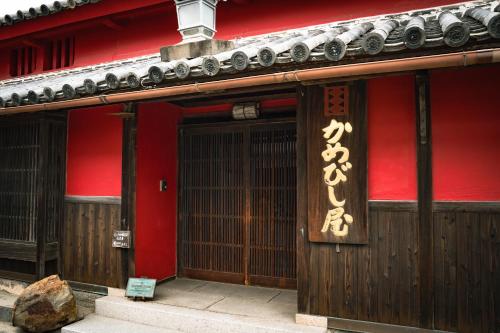 an entrance to a building with a red wall and a door at A 270-year-old soy sauce maker and a 100-year-old house collaborate to create Kamebishi-tei in Higashikagawa