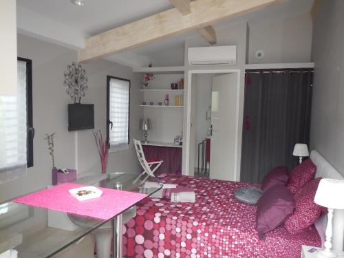 uma sala de estar com uma cama rosa e uma mesa em le gîte Lou Jas em Eyragues