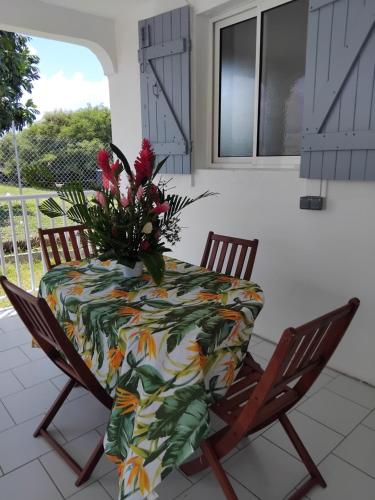 una mesa y sillas con un jarrón de flores. en Résidence belle place, en Saint-François