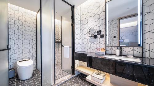 Un baño con inodoro, lavabo y espejo. en Microtel by Wyndham Anshun Xixiu, en Anshun