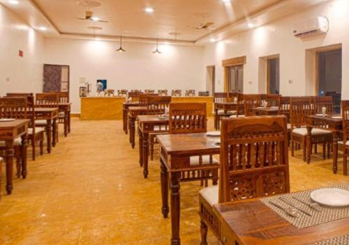 un restaurant vide avec des tables et des chaises en bois dans l'établissement desert sweet resort Jaisalmer, à Jaisalmer