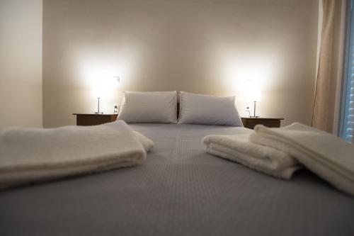 a white bed with white sheets and pillows on it at Nikolatos Apartments in Lóngos
