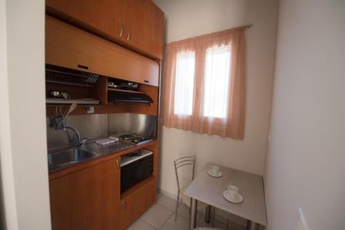 a kitchen with wooden cabinets and a sink and a table at Nikolatos Apartments in Lóngos