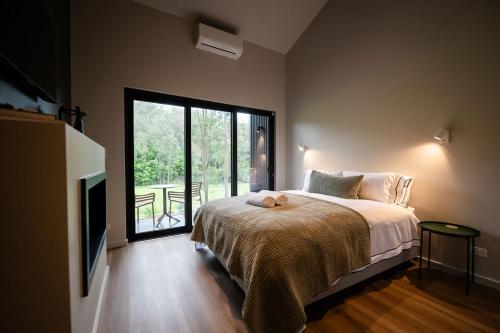 a bedroom with a bed and a large window at Redwood Park - Luxury Off Grid Accommodation in Wollombi