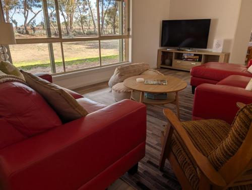 Il comprend un salon doté d'un mobilier rouge et d'une télévision à écran plat. dans l'établissement Willa Villa Bush Retreat - Gol Gol, à Gol Gol