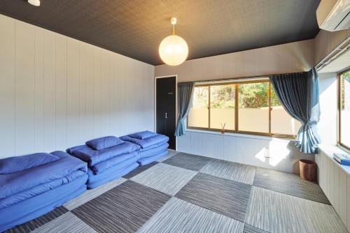 sala de estar con sofás azules y ventana en 星が降りそそぐVilla 都心から70分 にぎわいOK完全プライベート空間 吹抜けサウナ 最大8名 雨でもBBQ 天体観測 田園が広がるぽつんと宿, en Kimitsu