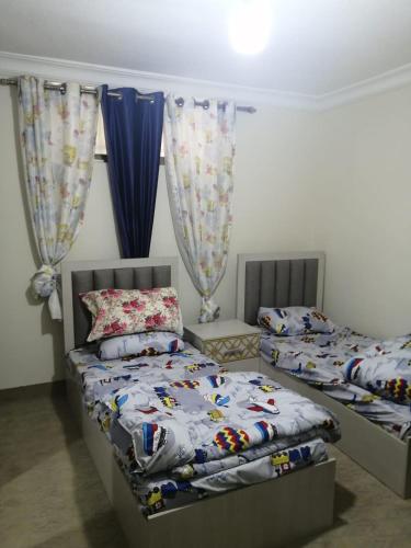 a bedroom with two twin beds and a window at الرائد للشقق المفروشة in Amman