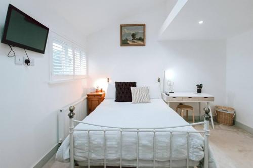Un dormitorio blanco con una cama y un escritorio. en The Pembroke Studio By Richmond Park, en Kingston upon Thames